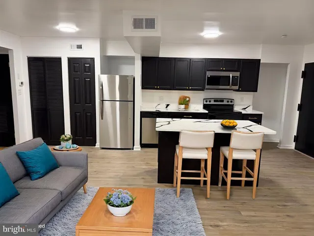 a living room with stainless steel appliances kitchen island granite countertop a dining table and chairs