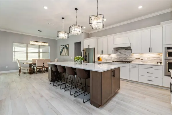 a kitchen with stainless steel appliances kitchen island granite countertop a stove a sink a dining table and chairs with wooden floor