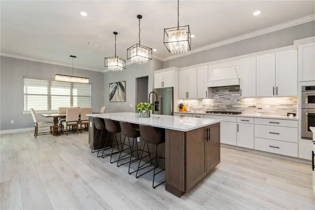 a kitchen with stainless steel appliances kitchen island granite countertop a stove a sink a dining table and chairs with wooden floor