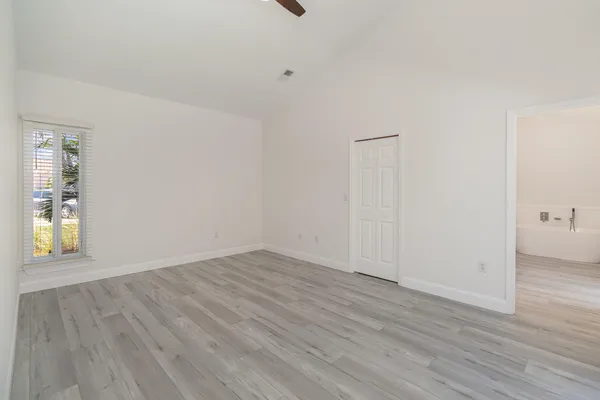 an empty room with wooden floor and windows