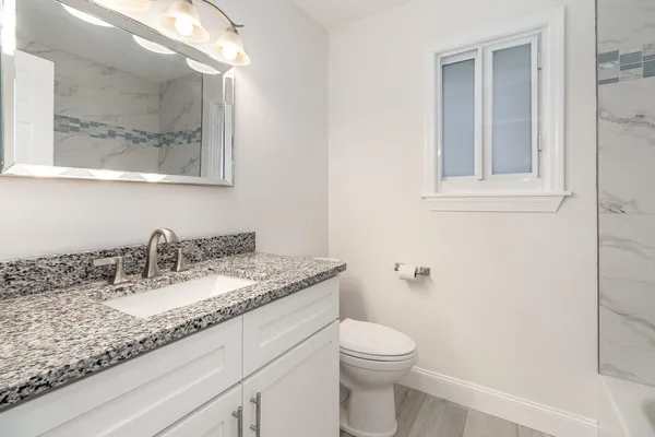 a bathroom with a granite countertop sink and a mirror