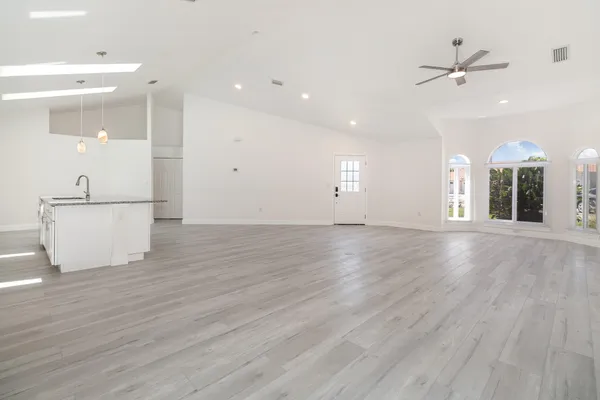 an empty room with wooden floor and a ceiling fan