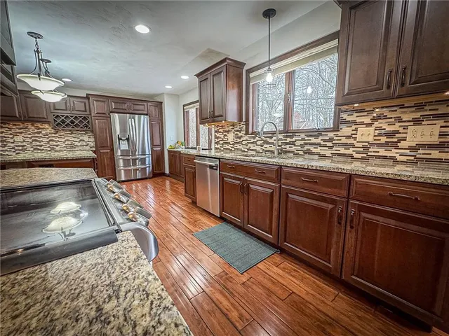 a kitchen with stainless steel appliances granite countertop wooden cabinets a stove and a sink