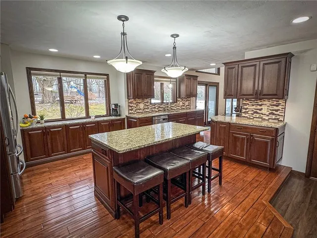 a kitchen with a stove a sink wooden floor dining table and chairs