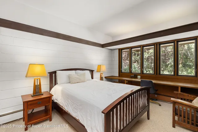 a bedroom with a bed a lamp and a large window with outer view