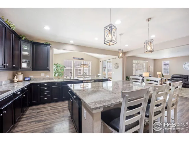 a kitchen with stainless steel appliances kitchen island granite countertop a table chairs and wooden cabinets