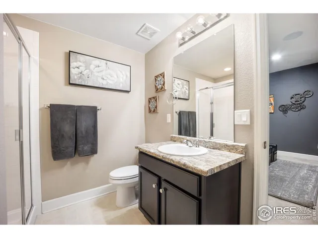 a bathroom with a granite countertop sink toilet and mirror