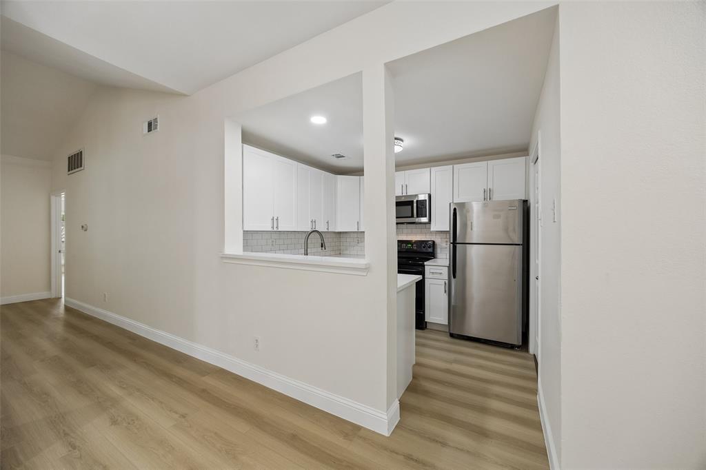 12660 Hillcrest Road, Unit 7205 Dallas, TX 75230 - Photo 18 of 25 Kitchen pass-through with white cabinetry and light wood-finish flooring