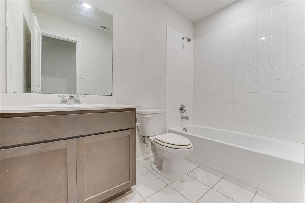 517 Milo Way Royse City, TX 75189 - Photo 11 of 34 Bathroom featuring a vanity with a white countertop and undermount sink, a large wall-mounted mirror, a commode, and a tub-shower combination with white subway tile surround