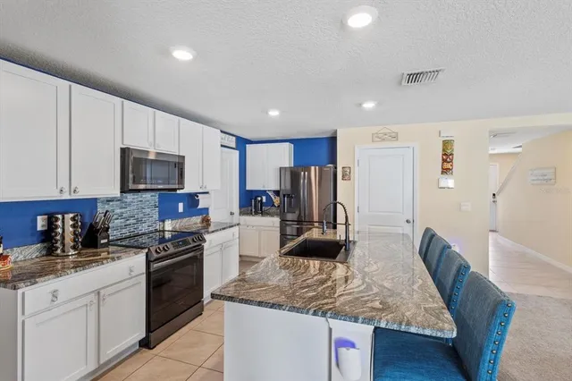 a kitchen with stainless steel appliances granite countertop a sink refrigerator and microwave