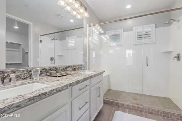 a bathroom with a granite countertop sink a mirror and a shower