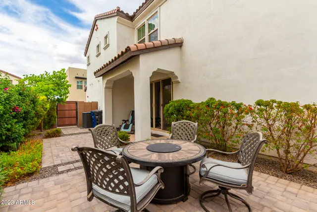 a view of a patio with table and chairs with potted plants and wooden fence
