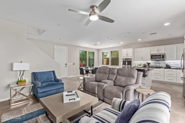 a living room with furniture kitchen view and a chandelier