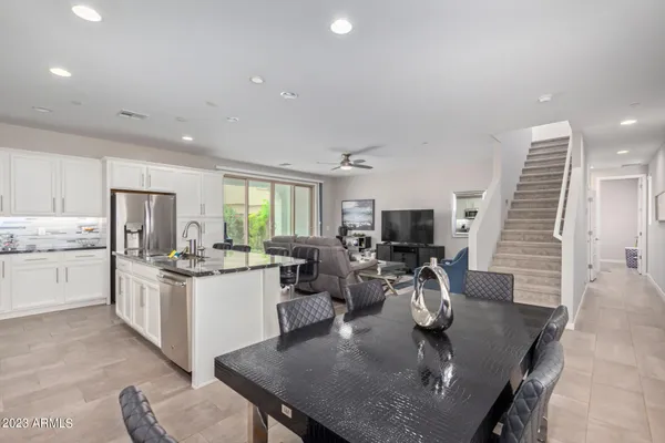 a kitchen with a stove a sink dishwasher a dining table and chairs with wooden floor