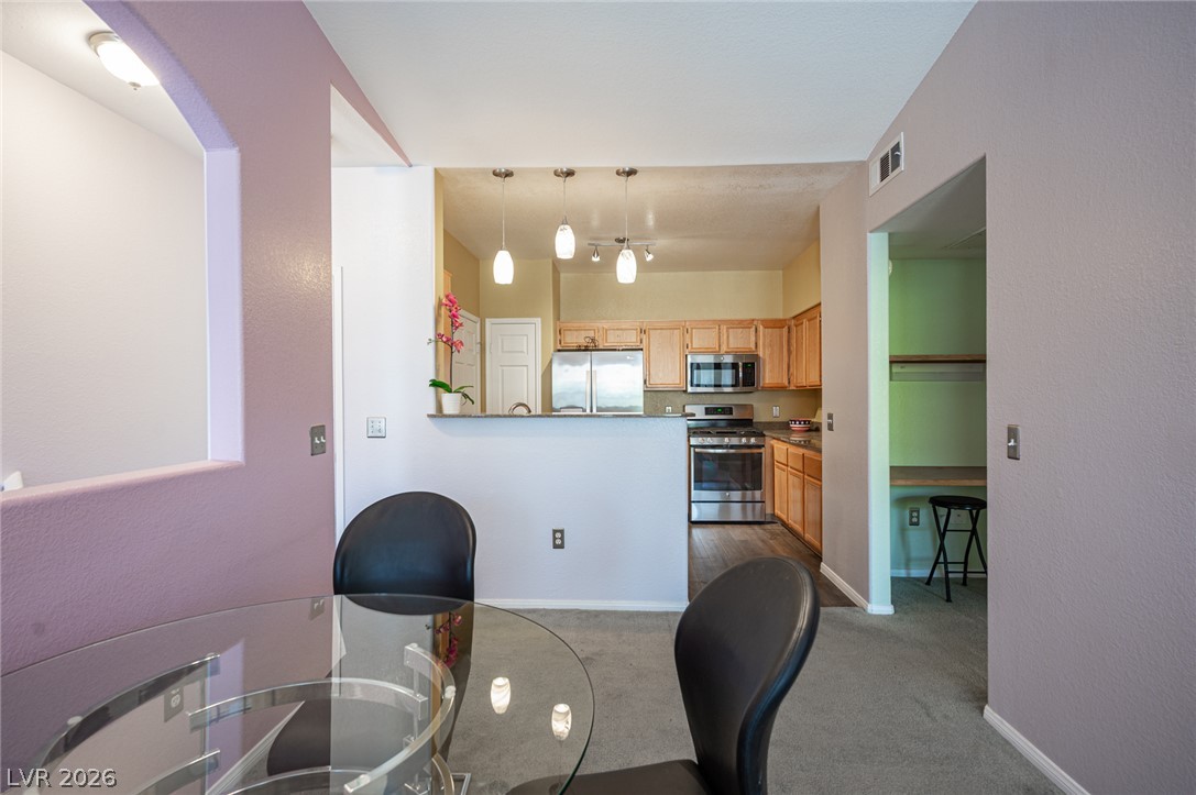 10550 West Alexander Road, Unit 2014 Las Vegas, NV 89129 - Photo 12 of 35 An open concept kitchen features stainless steel appliances and abundant natural wood cabinetry.