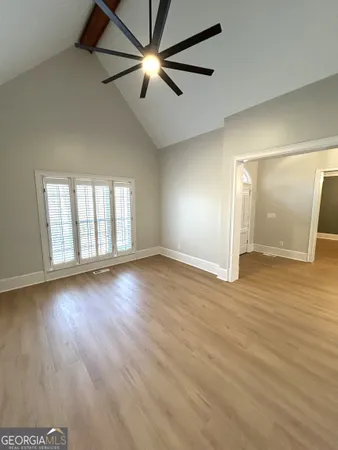 a view of an empty room with wooden floor and a window