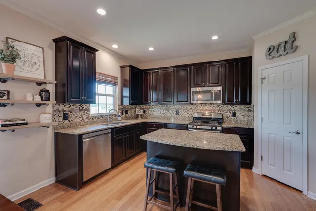 a kitchen with kitchen island granite countertop wooden cabinets and a refrigerator