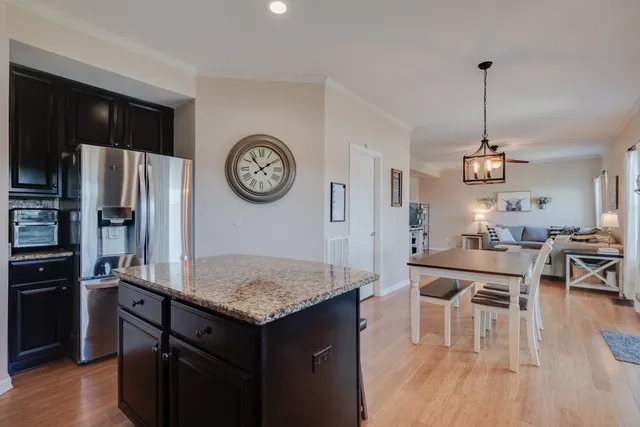 a kitchen with a refrigerator a stove top oven a clock and wooden floor