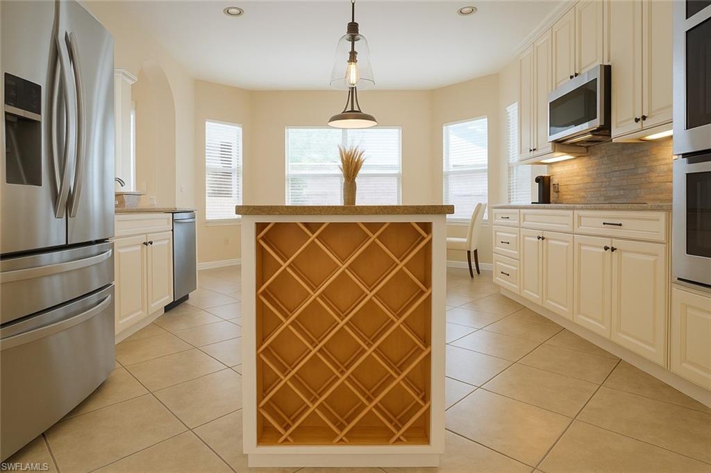 1975 San Marco Road Marco Island, FL 34145 - Photo 11 of 46 Kitchen with stainless steel appliances, light tile patterned flooring, decorative light fixtures, tasteful backsplash, and a center island