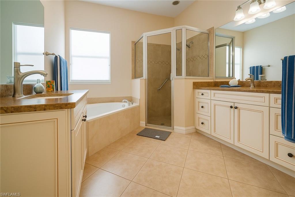 1975 San Marco Road Marco Island, FL 34145 - Photo 23 of 46 Bathroom featuring light tile patterned floors, two vanities, a shower stall, and a bath