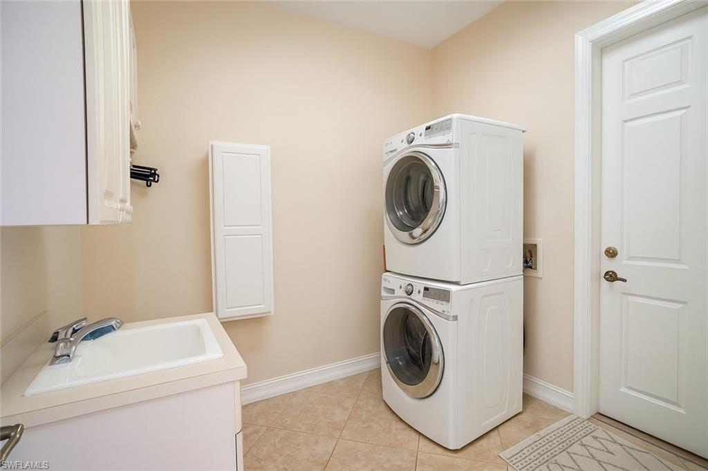1975 San Marco Road Marco Island, FL 34145 - Photo 31 of 46 Laundry area with estacked washer and dryer, light tile patterned floors, and cabinet space