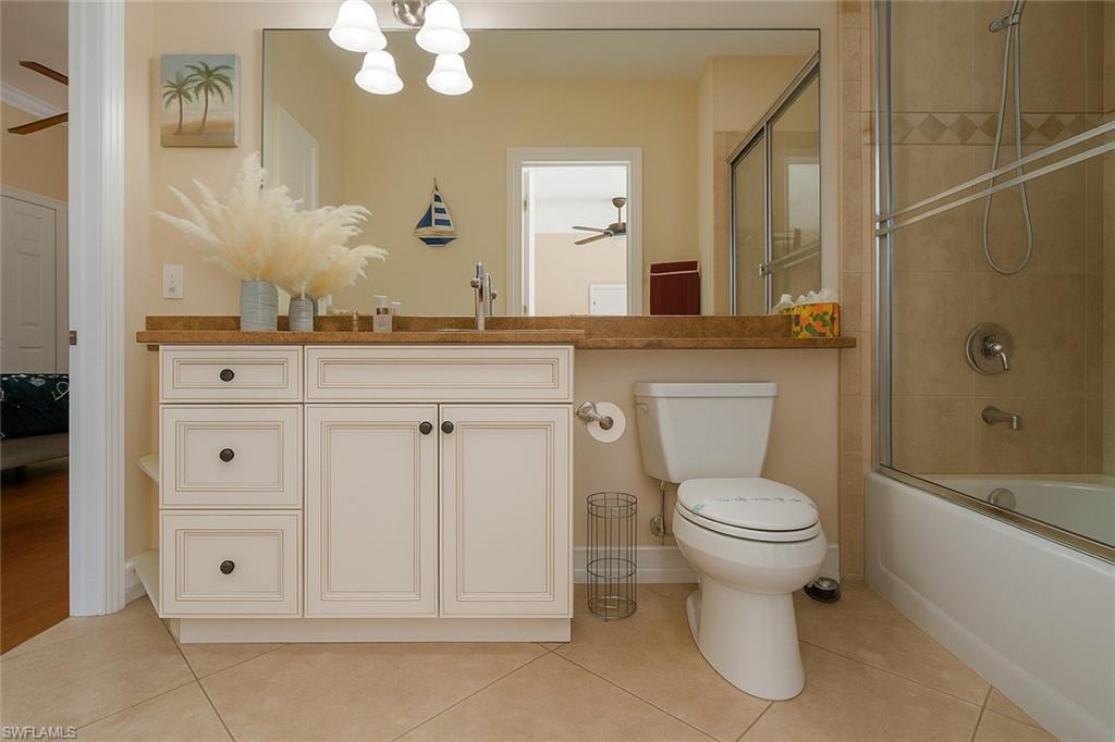 1975 San Marco Road Marco Island, FL 34145 - Photo 35 of 46 Bathroom featuring light tile patterned floors, combined bath / shower with glass door, vanity, a chandelier, and a ceiling fan