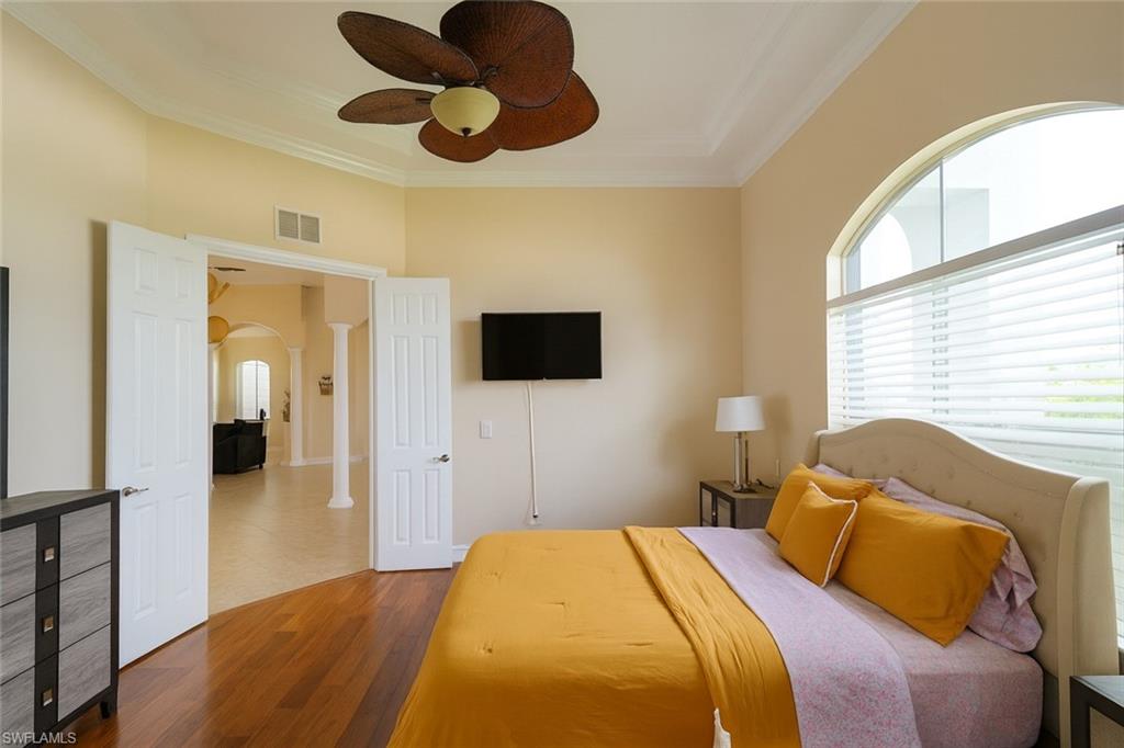 1975 San Marco Road Marco Island, FL 34145 - Photo 41 of 46 Bedroom featuring arched walkways, wood finished floors, a ceiling fan, and ornamental molding