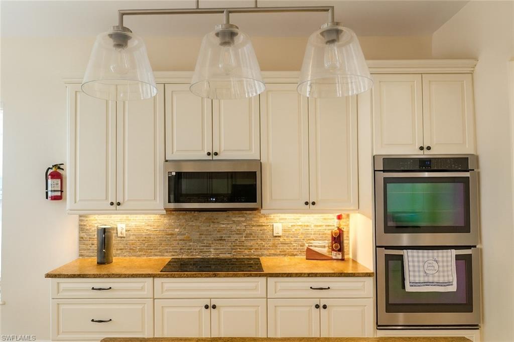 1975 San Marco Road Marco Island, FL 34145 - Photo 9 of 46 Kitchen featuring stainless steel appliances, backsplash, light stone counters, and white cabinetry