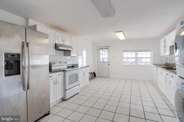 a large white kitchen with white cabinets appliances and a window