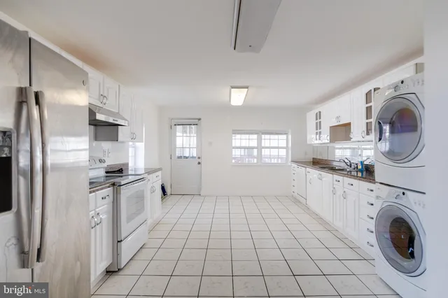 a kitchen with granite countertop a sink a stove top oven and refrigerator