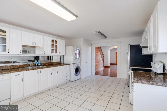 a large white kitchen with granite countertop a sink