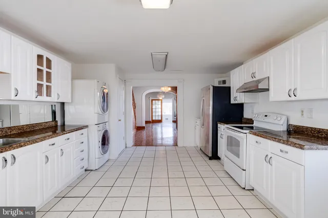 a kitchen with granite countertop white cabinets a sink dishwasher and a stove with wooden floor