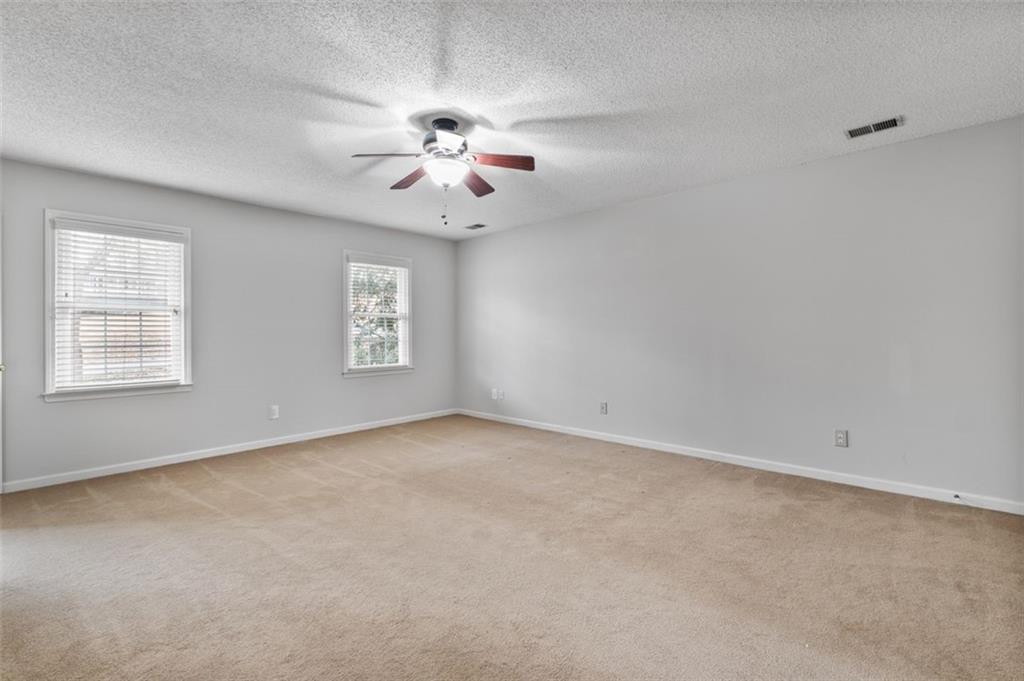 4803 Tarleton Drive Southwest Lilburn, GA 30047 - Photo 13 of 32 an empty room with windows and chandelier fan