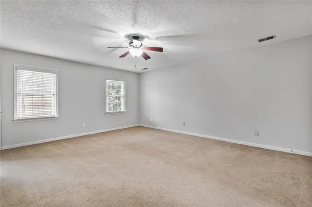 an empty room with windows and chandelier fan