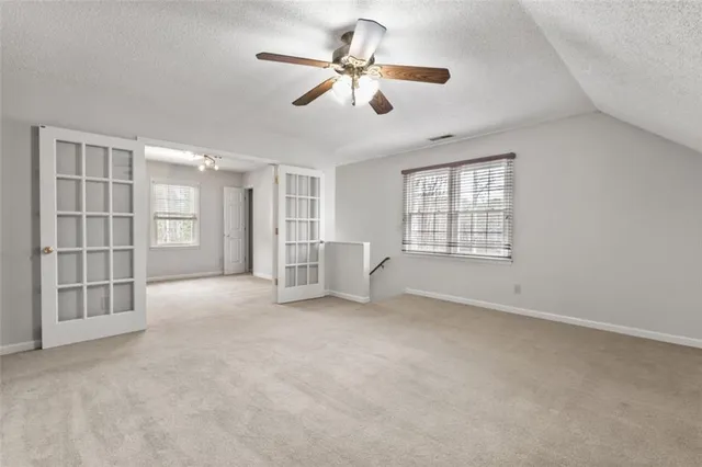 a view of an empty room with a window and a kitchen