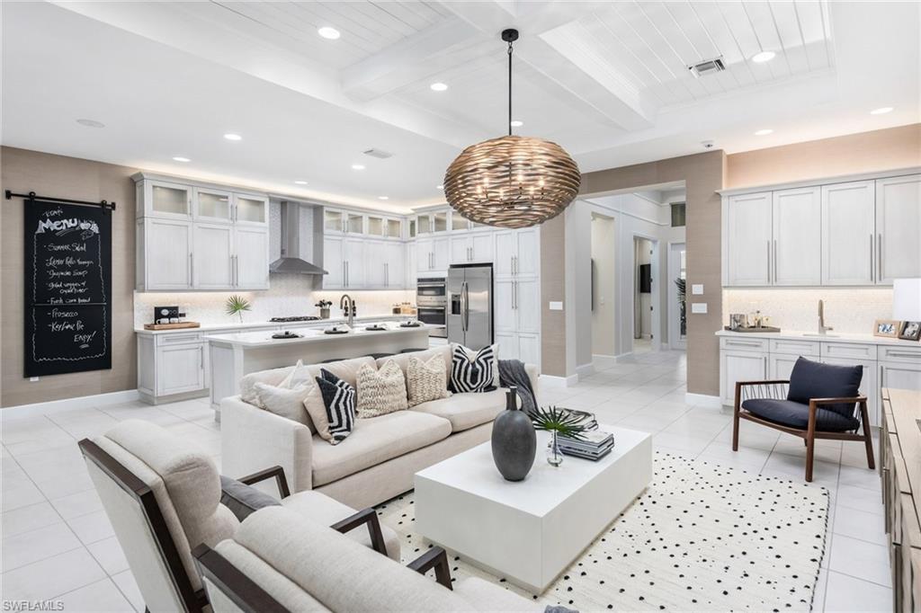 a living room with stainless steel appliances granite countertop furniture a rug kitchen view and a chandelier