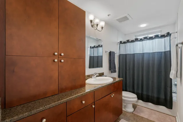 a bathroom with a sink a toilet a mirror and shower