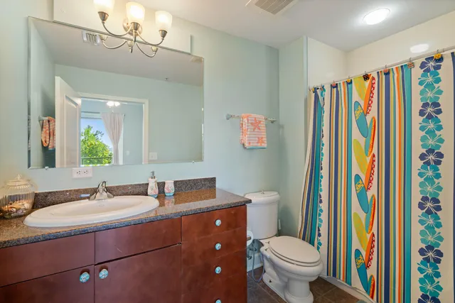a bathroom with a sink a toilet a mirror and shower curtain