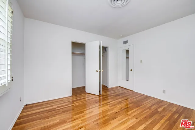 a view of empty room with wooden floor and window
