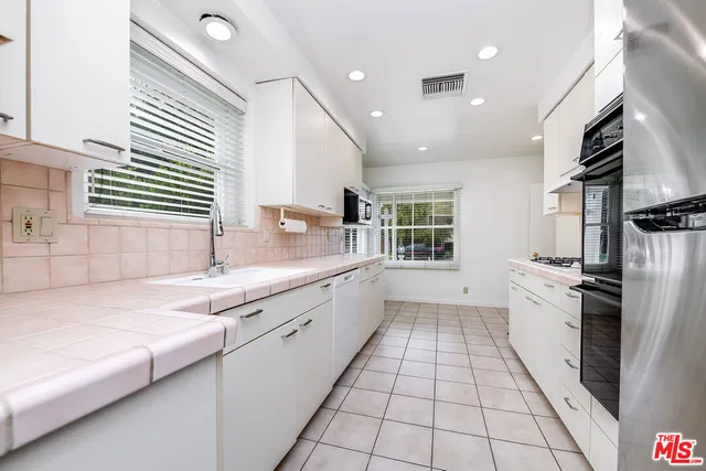 a large white kitchen with a sink and stainless steel appliances