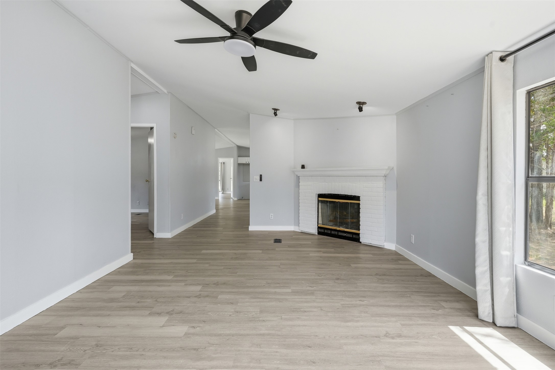 154 Antioch Road Smithville, TX 78957 - Photo 19 of 32 A whitewashed fireplace anchors this spacious living area with light wood flooring and generous natural illumination.