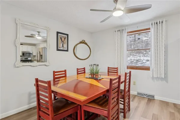a dining room with wooden floor a chandelier fan a wooden table and chairs