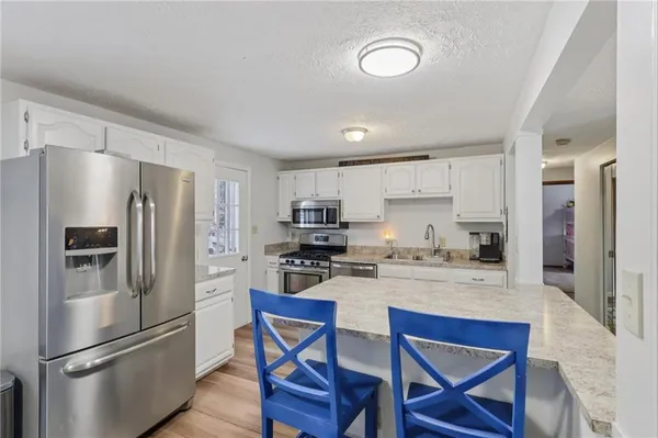 a kitchen with stainless steel appliances a stove a sink a dining table and chairs