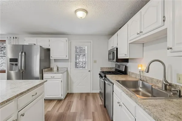 a kitchen with granite countertop white cabinets and stainless steel appliances
