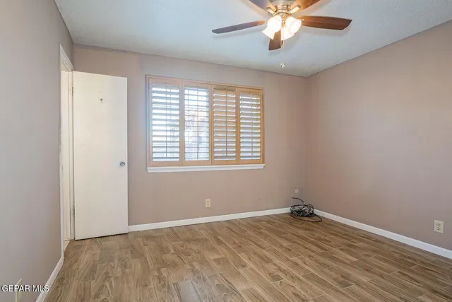 a view of empty room with wooden floor and fan