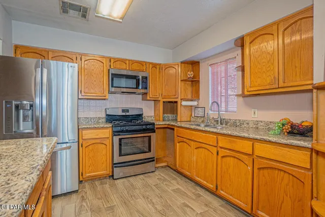 a kitchen with granite countertop cabinets stainless steel appliances a sink and a window