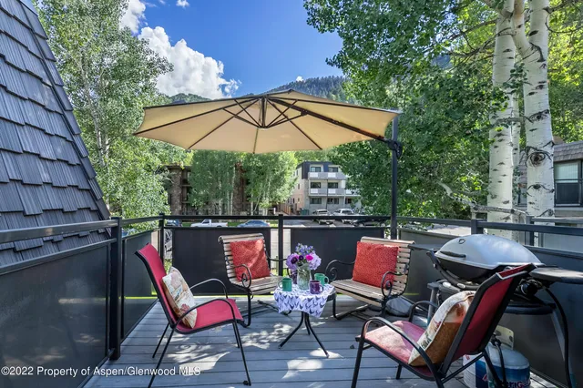 an outdoor sitting area with furniture and umbrella