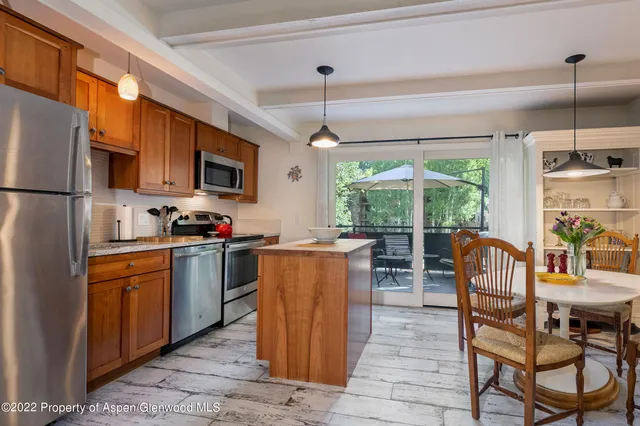 a kitchen with kitchen island granite countertop wooden cabinets a dining table and stainless steel appliances