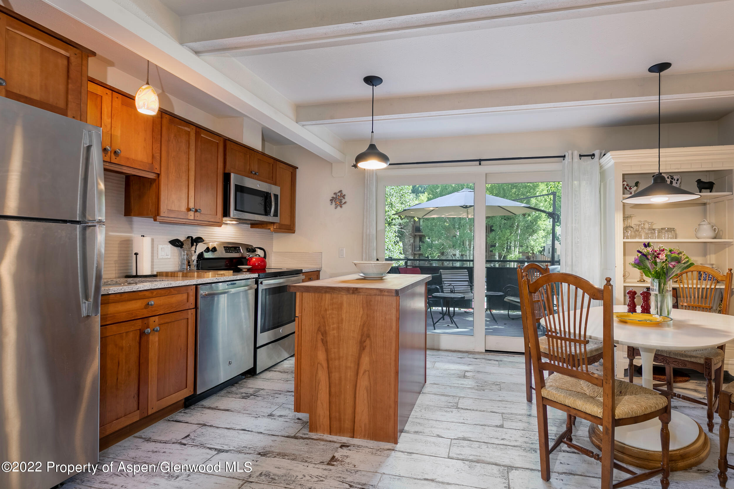 124 East Durant Avenue, Unit 4 Aspen, CO 81611 - Photo 7 of 13 a kitchen with kitchen island granite countertop wooden cabinets a dining table and stainless steel appliances