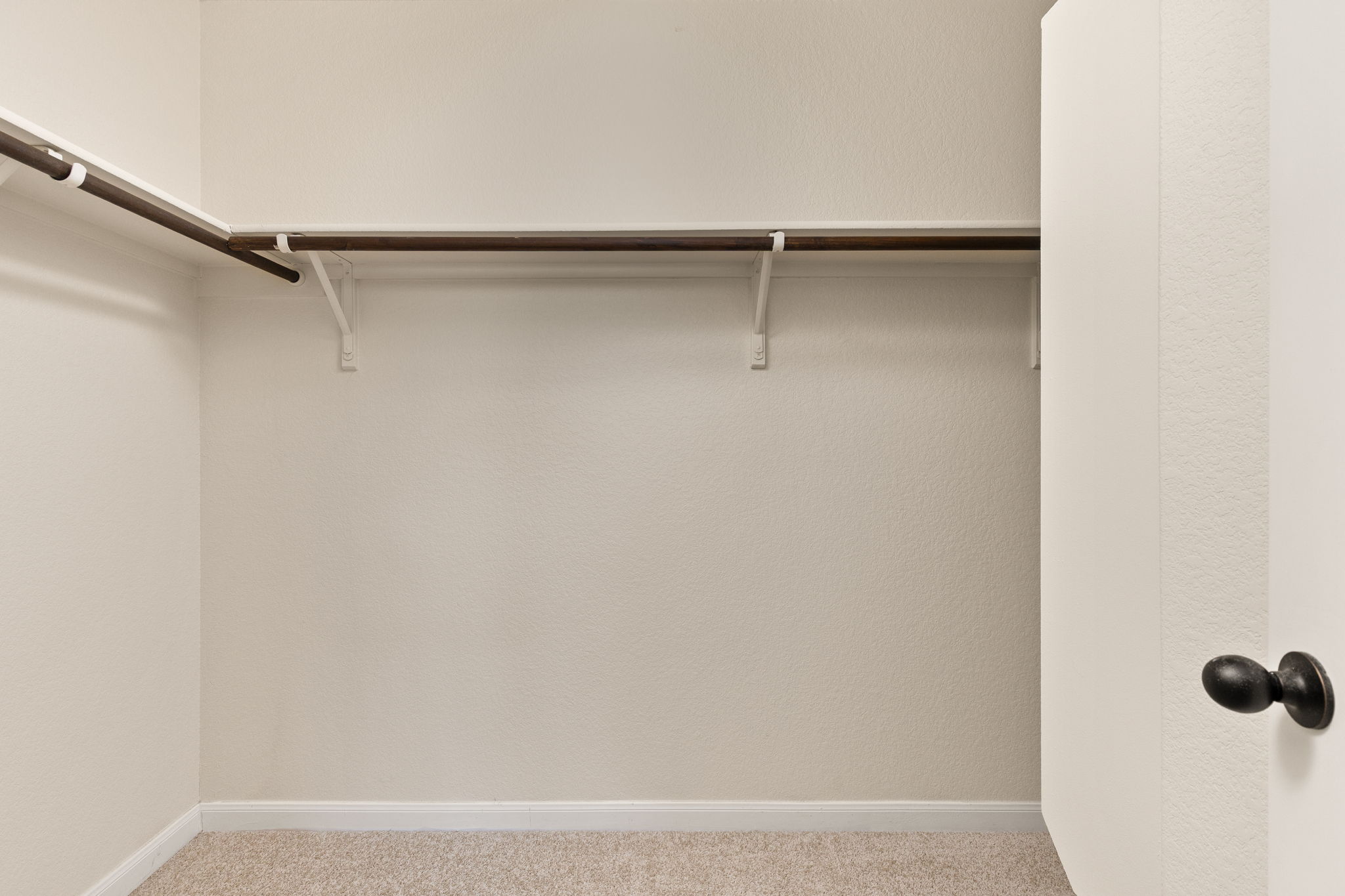 2400 Leonards Pass Leander, TX 78641 - Photo 31 of 40 An empty, well-kept closet space with hanging rods and carpeted flooring awaits your personal touch.